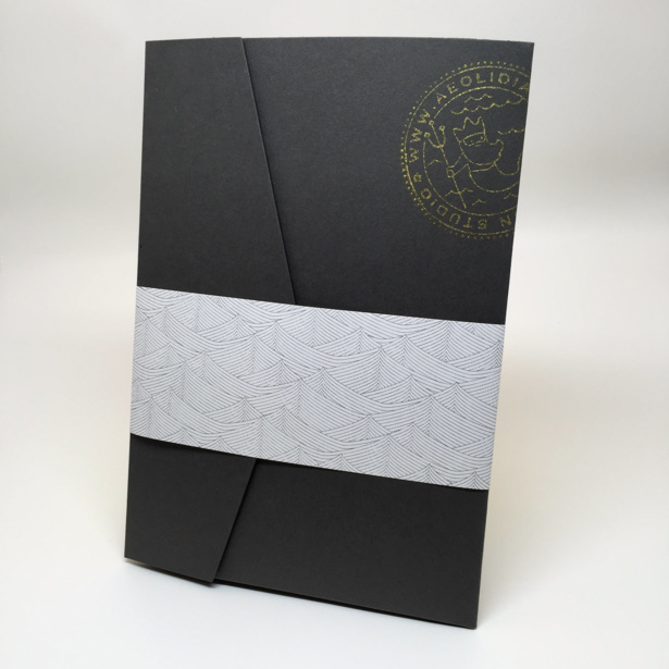 The welcome folder, all packed up with our gold foil print and information inside, wearing a custom wave patterned belly band